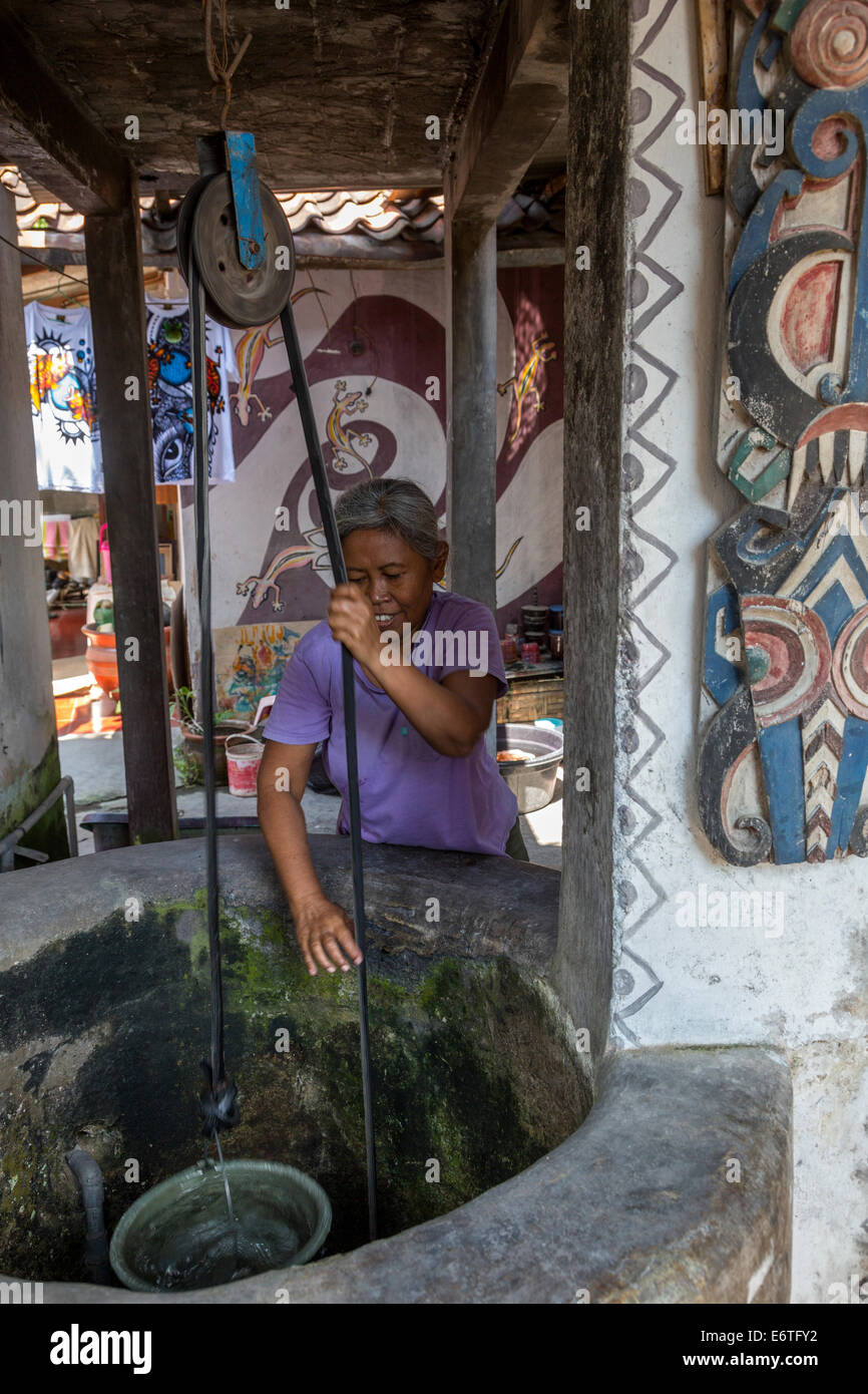 Yogyakarta, Java, Indonesien.  Frau Zeichnung Wasser aus ihrem privaten Brunnen in Nachbarschaft Family Home. Stockfoto