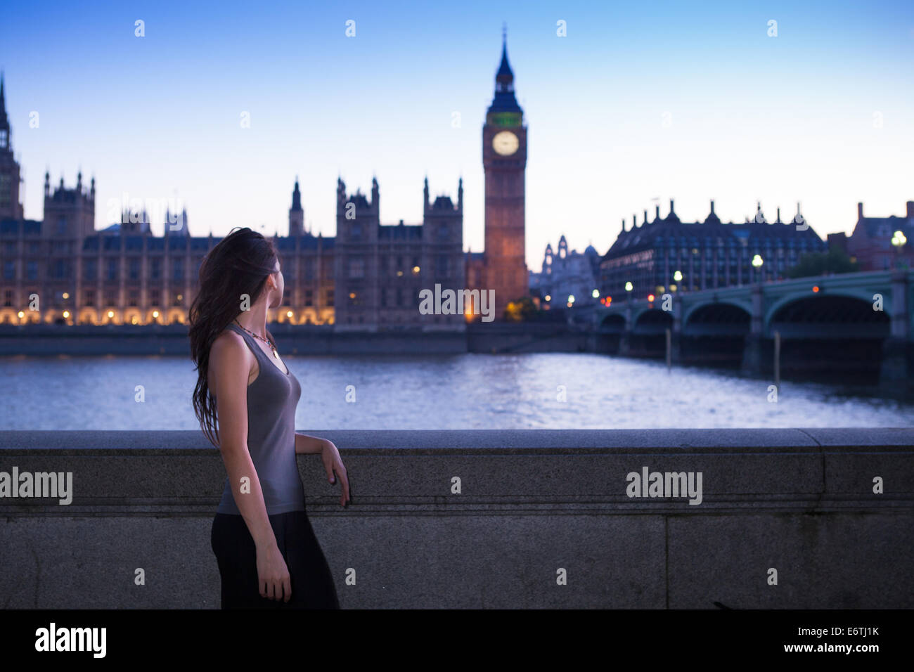 Eine junge Frau stand vor den Houses of Parliament in London in der Abenddämmerung Stockfoto