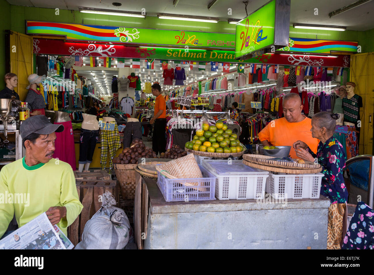 Yogyakarta, Java, Indonesien.  Kauf von Orangen an einem Obststand der Bürgersteig vor einem Bekleidungsgeschäft, Malioboro Street. Stockfoto