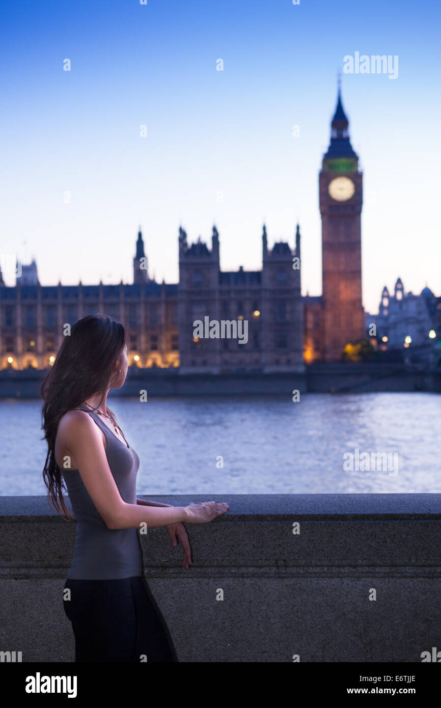 Eine junge Frau stand vor den Houses of Parliament in London in der Abenddämmerung Stockfoto