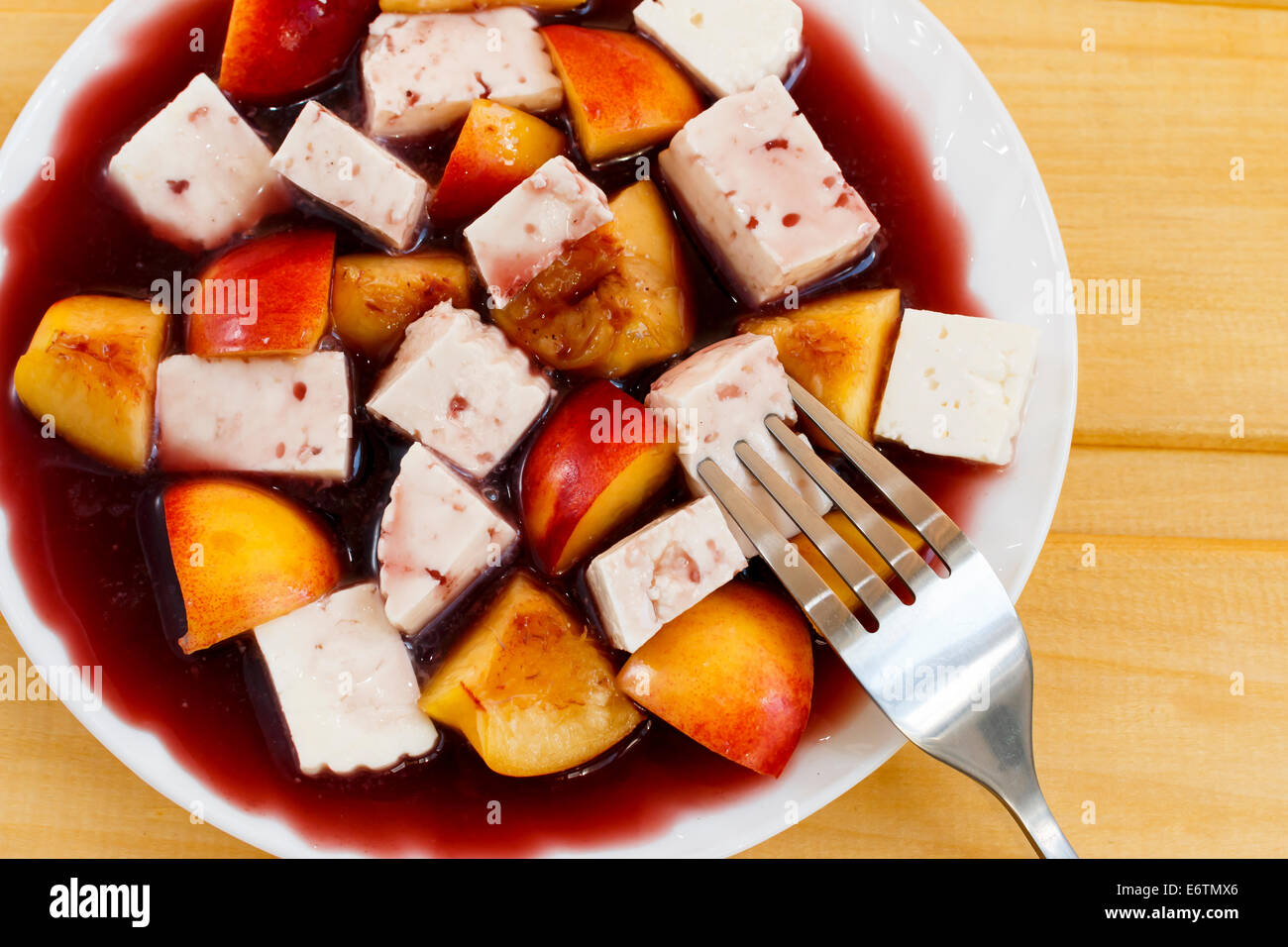 Käse und Pfirsiche in Rotweinsauce, Dessert Stockfoto