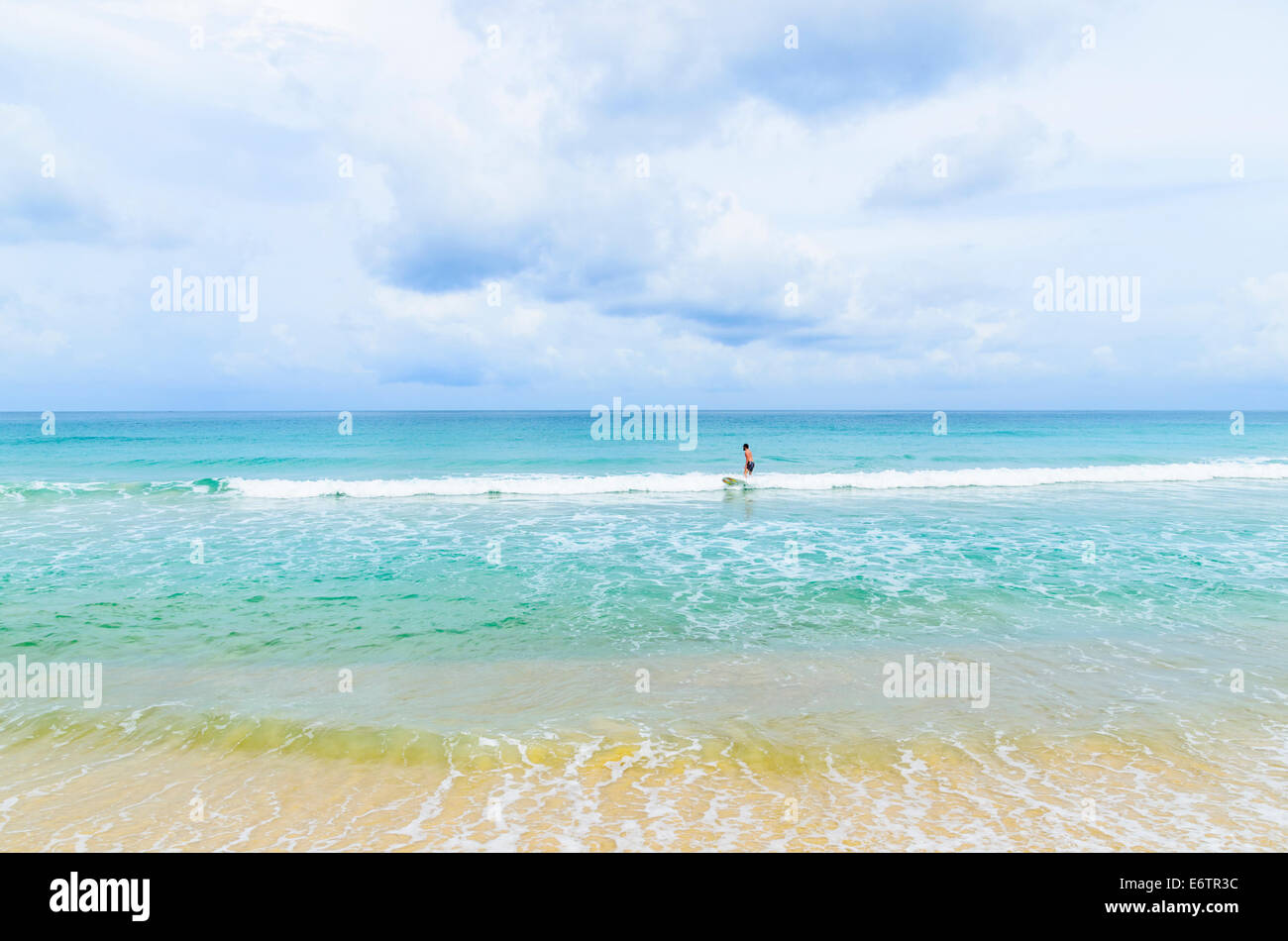 Einsamer Surfer, Surfen eine kleine Welle am Karon Beach, Phuket, Thailand Stockfoto