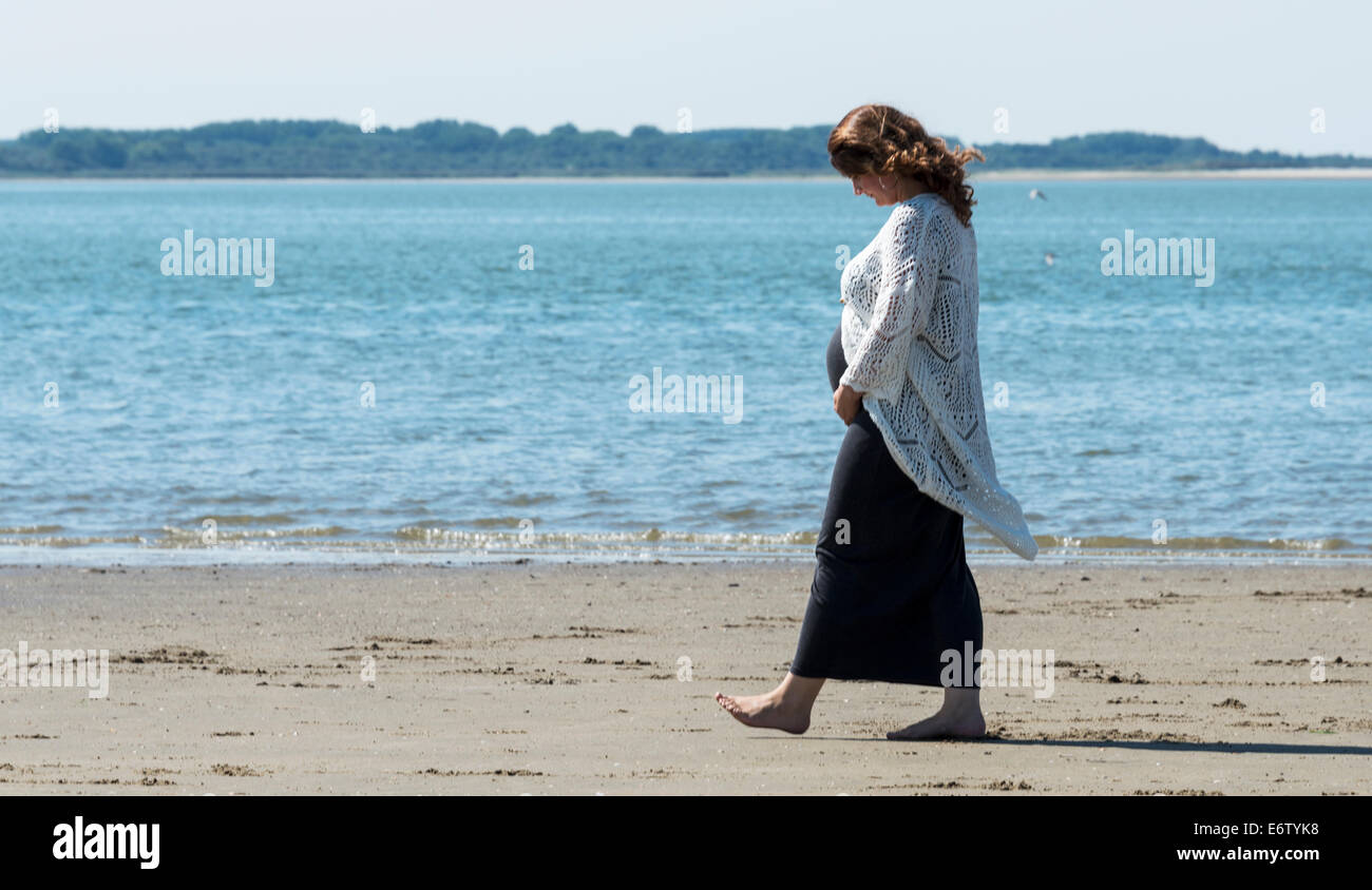 Schwangere Frau am Strand mit dem Meer als Hintergrund Stockfoto