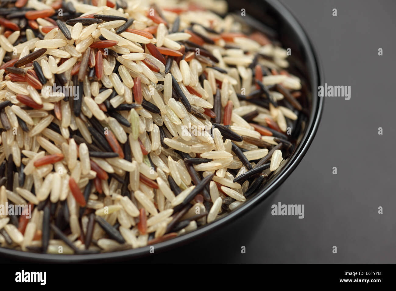 Gemischter Reis in einer schwarzen Schale auf schwarzem Hintergrund. Close-up. Stockfoto