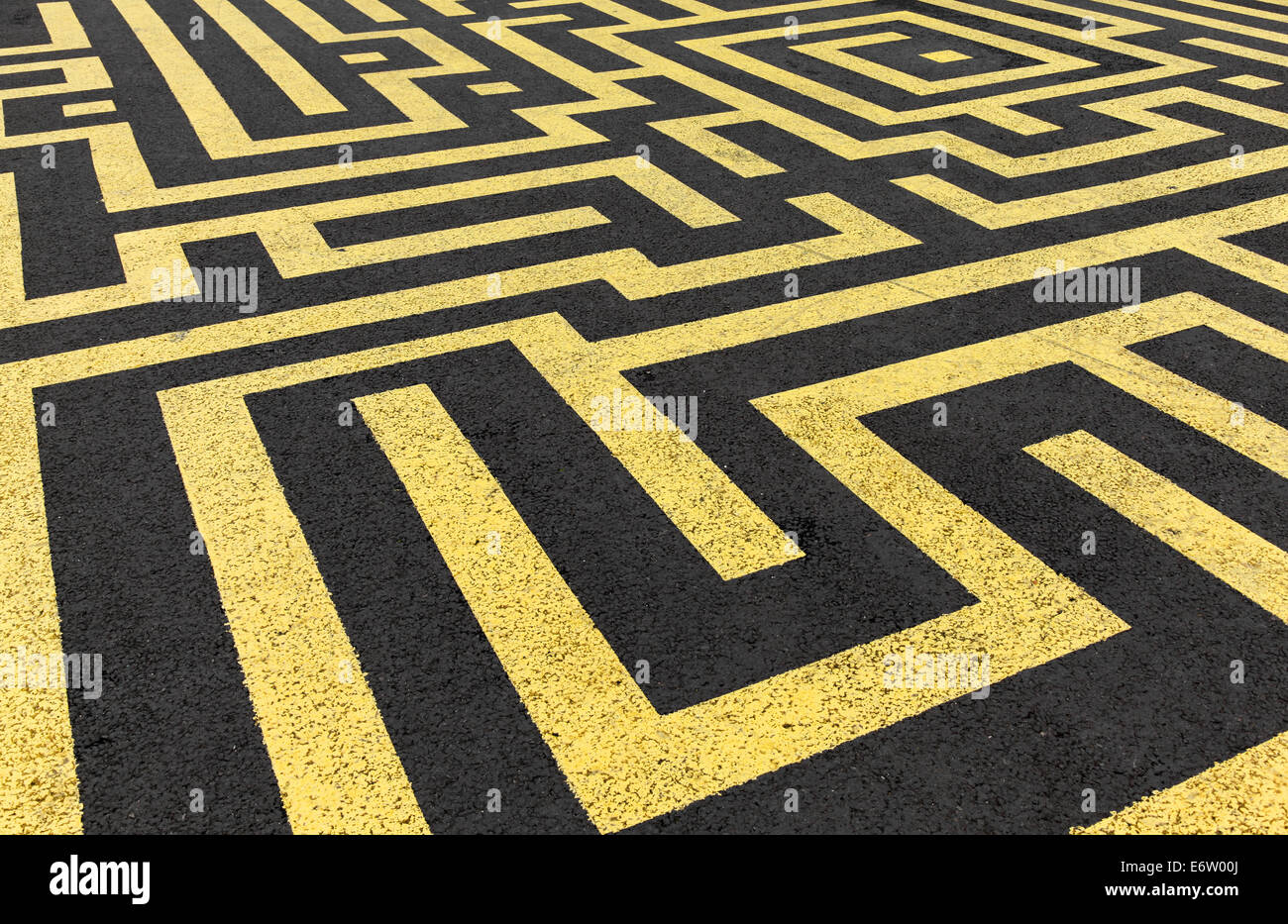 Gelbe Labyrinth gemalt auf einer schwarzen Asphaltstraße Stockfoto