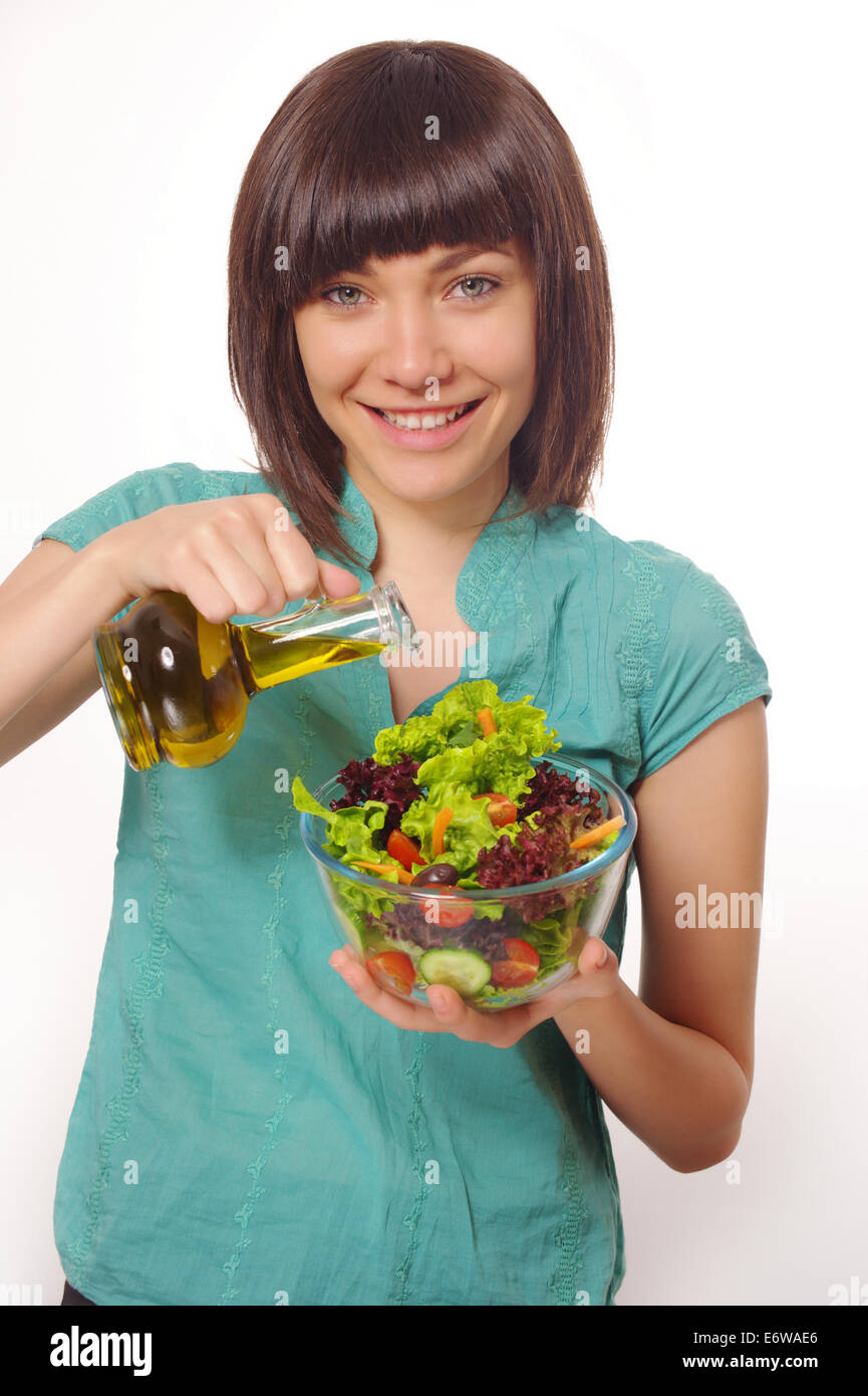 Glückliche Mädchen machen Salat mit Gemüse und Öl. Stockfoto