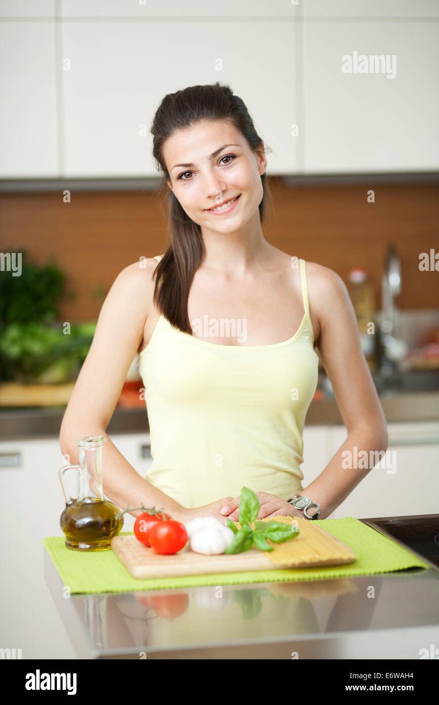 Junge Frau machen Salat mit Tomaten, Käse, Basilikum und Öl in der Küche. Stockfoto