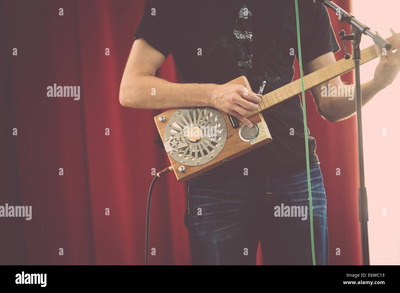 Ein Mann zupft eine sehr einzigartige Gitarre auf der Bühne. Stockfoto