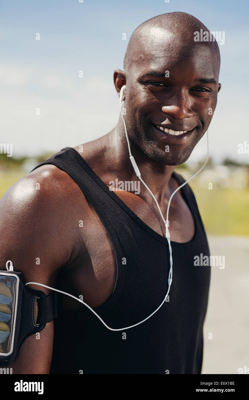 Bild von glücklicher junger Mann tragen Kopfhörer, Blick auf die Kamera zu Lächeln. Junge afrikanische männlichen Modell im freien angepasst. Muskulöse männliche runne Stockfoto