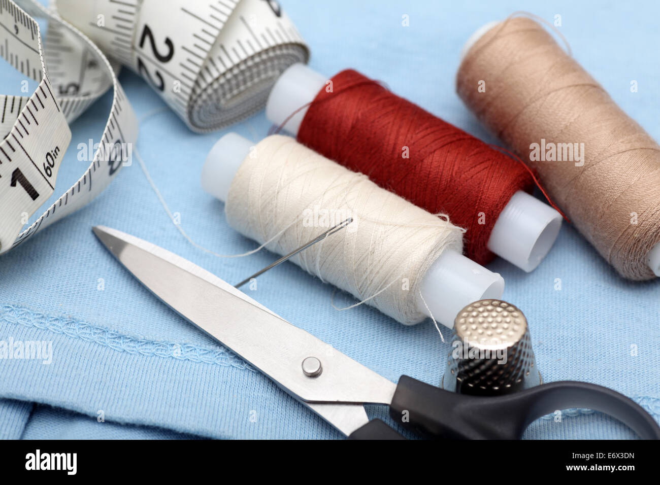 Nähen-Serie. Maßband, Fingerhut, Schere und Spule mit Nadel am Hemd. Closeup. Stockfoto