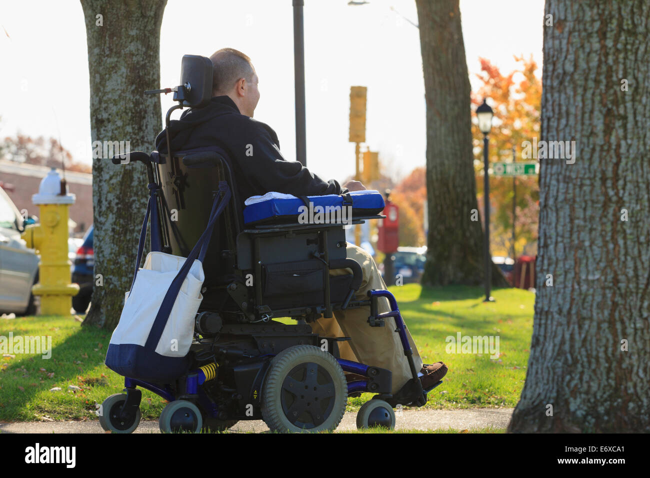 Mann mit Verletzungen des Rückenmarks und Arm mit Nervenschäden in motorisierten Rollstuhl in einem öffentlichen park Stockfoto