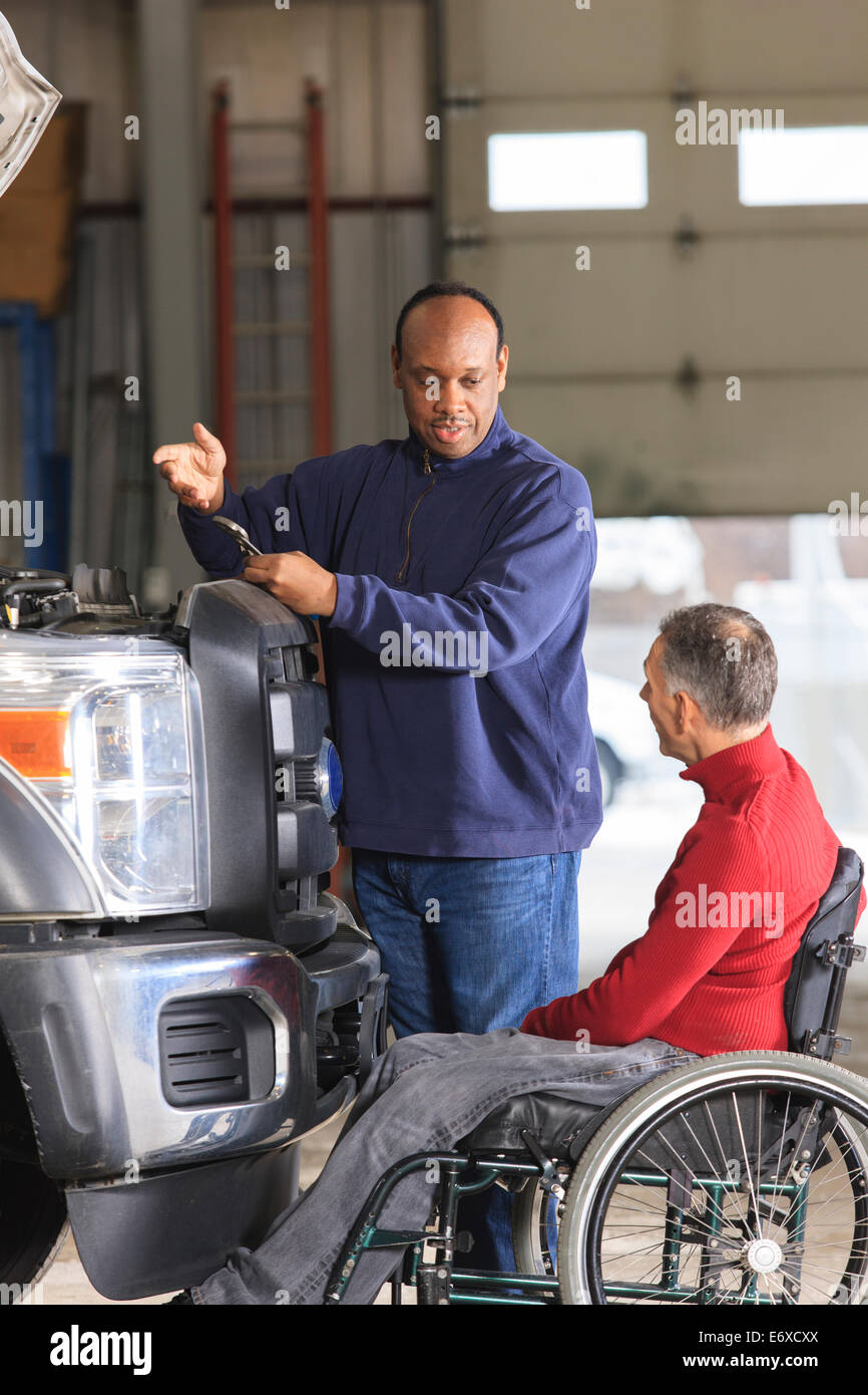 Kfz Wartungstechniker und Supervisor mit Rückenmarkverletzungen diskutieren Reparatur Stockfoto