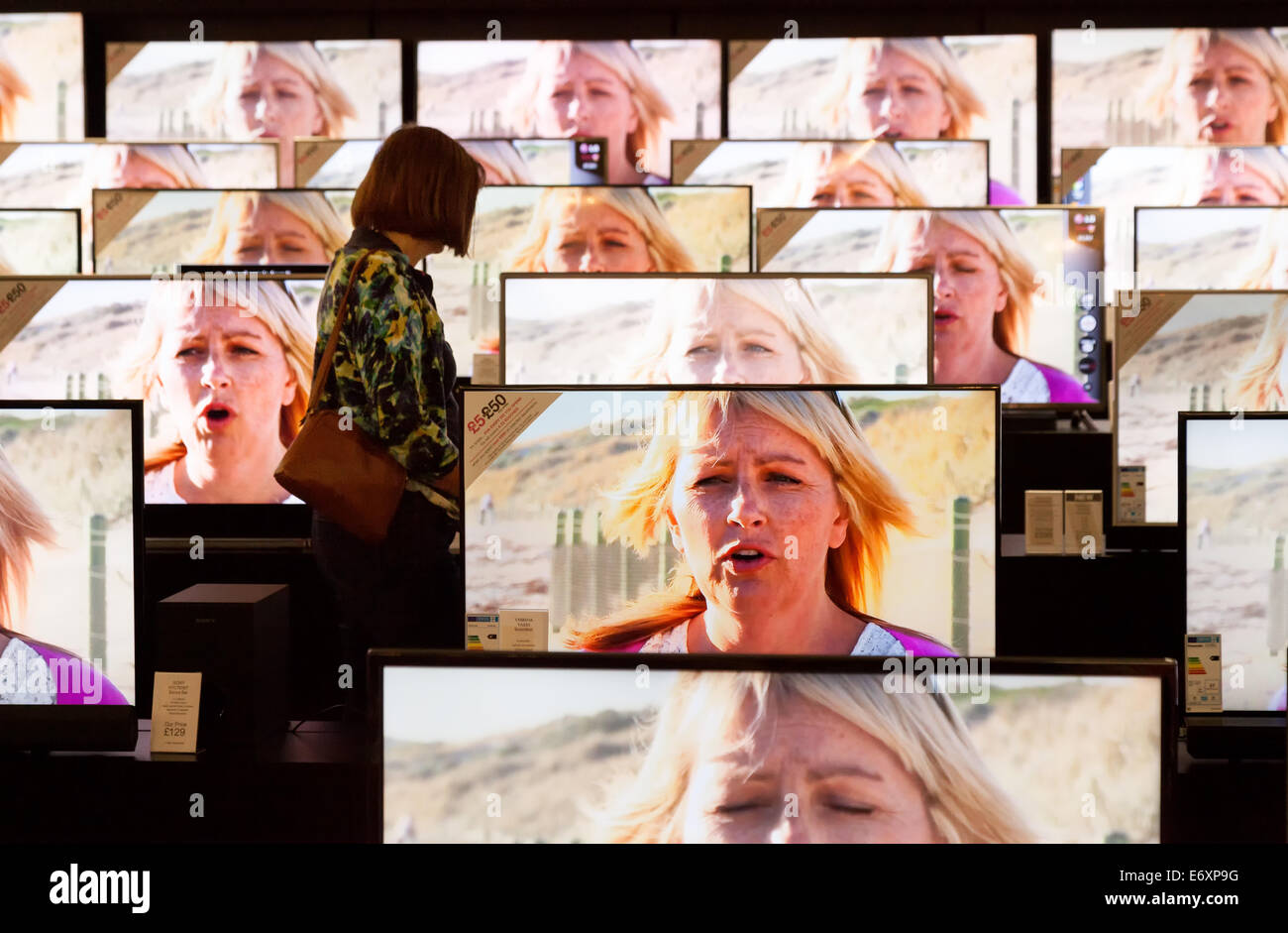 Eine Frau, die einen Fernseher in einem Elektronikladen in Großbritannien kauft. Einkauf von Unterhaltungselektronik in Großbritannien Stockfoto