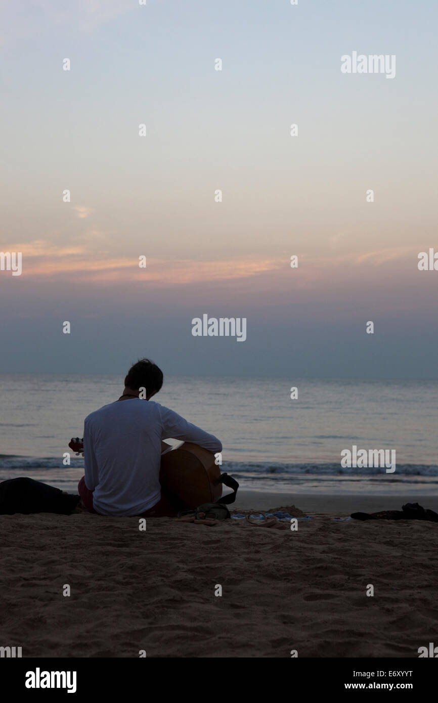 Touristen, die Gitarre zu spielen, am Strand bei Sonnenuntergang, Agonda, Goa, Indien Stockfoto