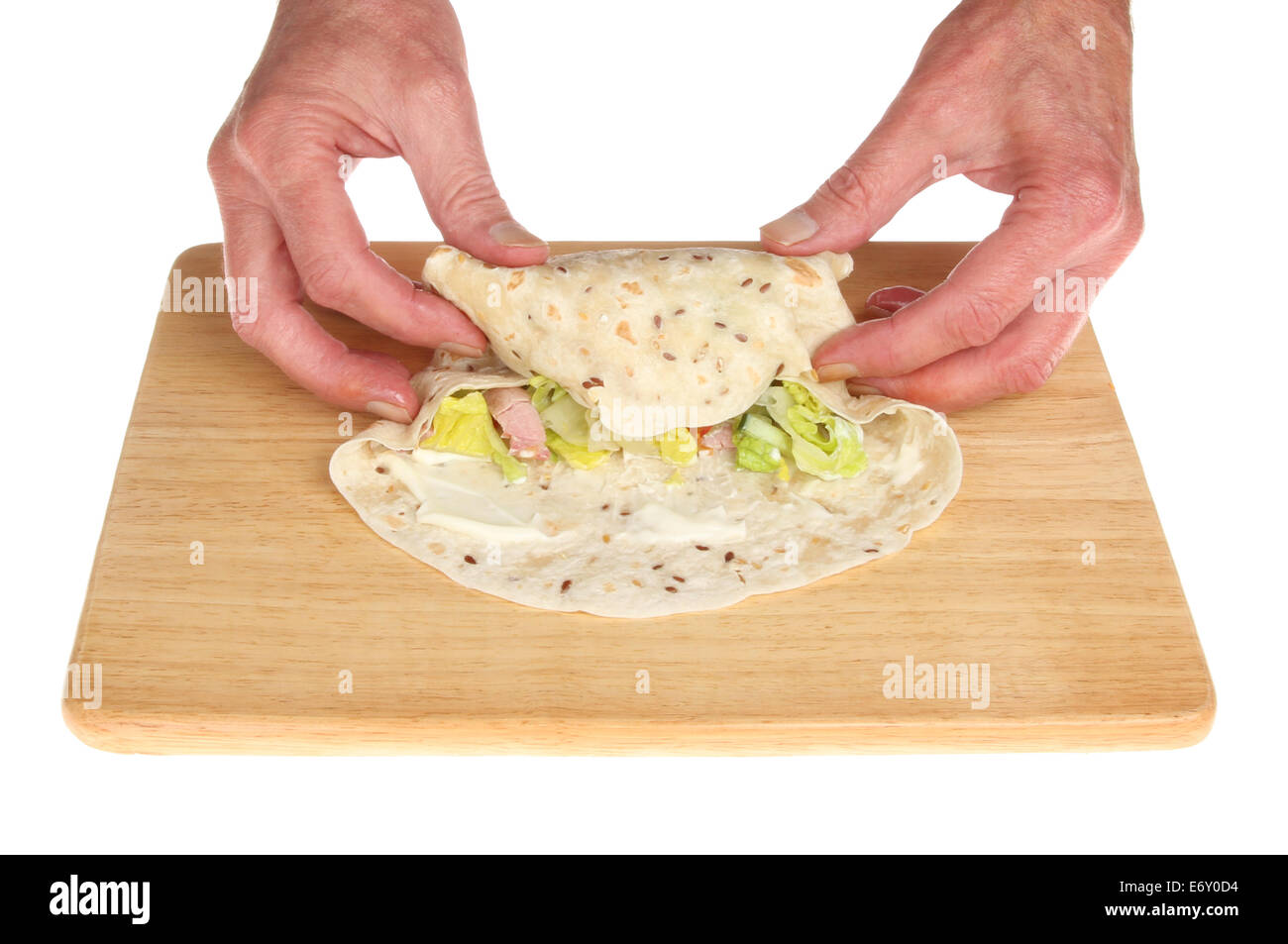 Nahaufnahme von ein paar Hände, einen Speck und Salat wickeln auf einem Holzbrett isoliert gegen weiße Brot Stockfoto