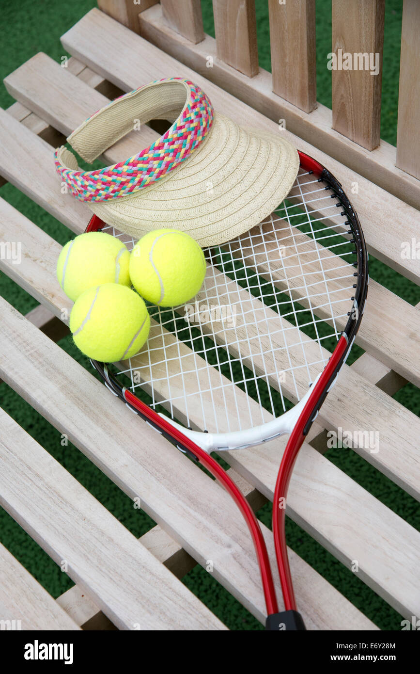 Tennis-Schläger-Kugeln und Sonnensegel auf einem hölzernen Sitz Stockfoto