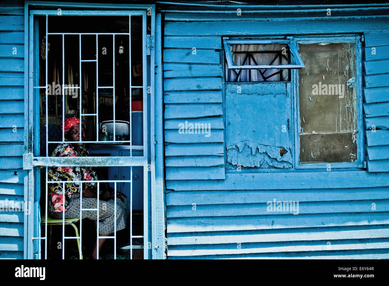 Frau sitzt in ihrer Hütte hinter einem vergitterten Tür, Township Langa, Cape Town, Südafrika, Afrika Stockfoto
