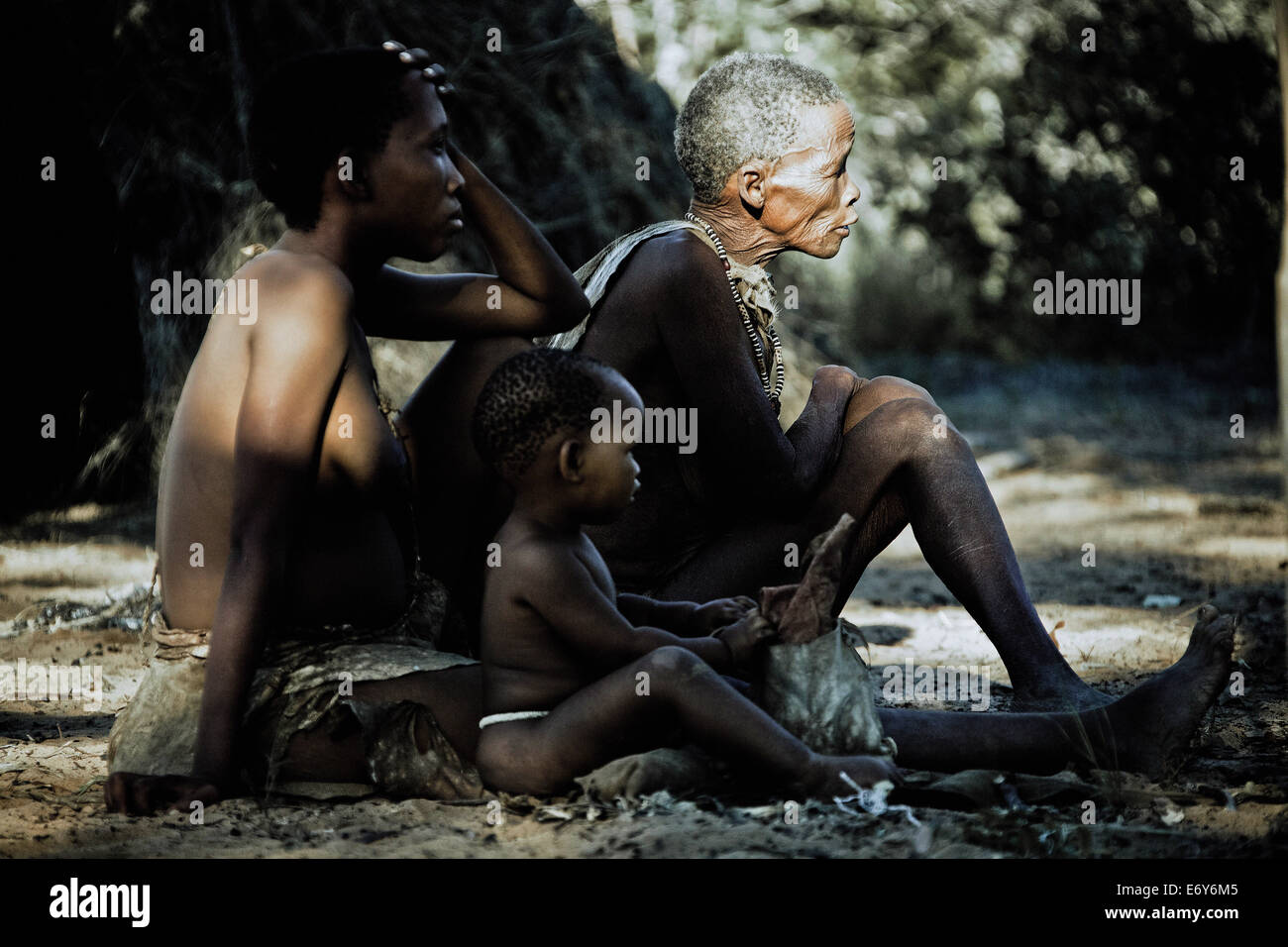Mutter, Tochter und Enkelin des Stammes San sitzen auf dem Boden vor ihrer Hütte, Otjozondjupa Region, Namibia, A Stockfoto