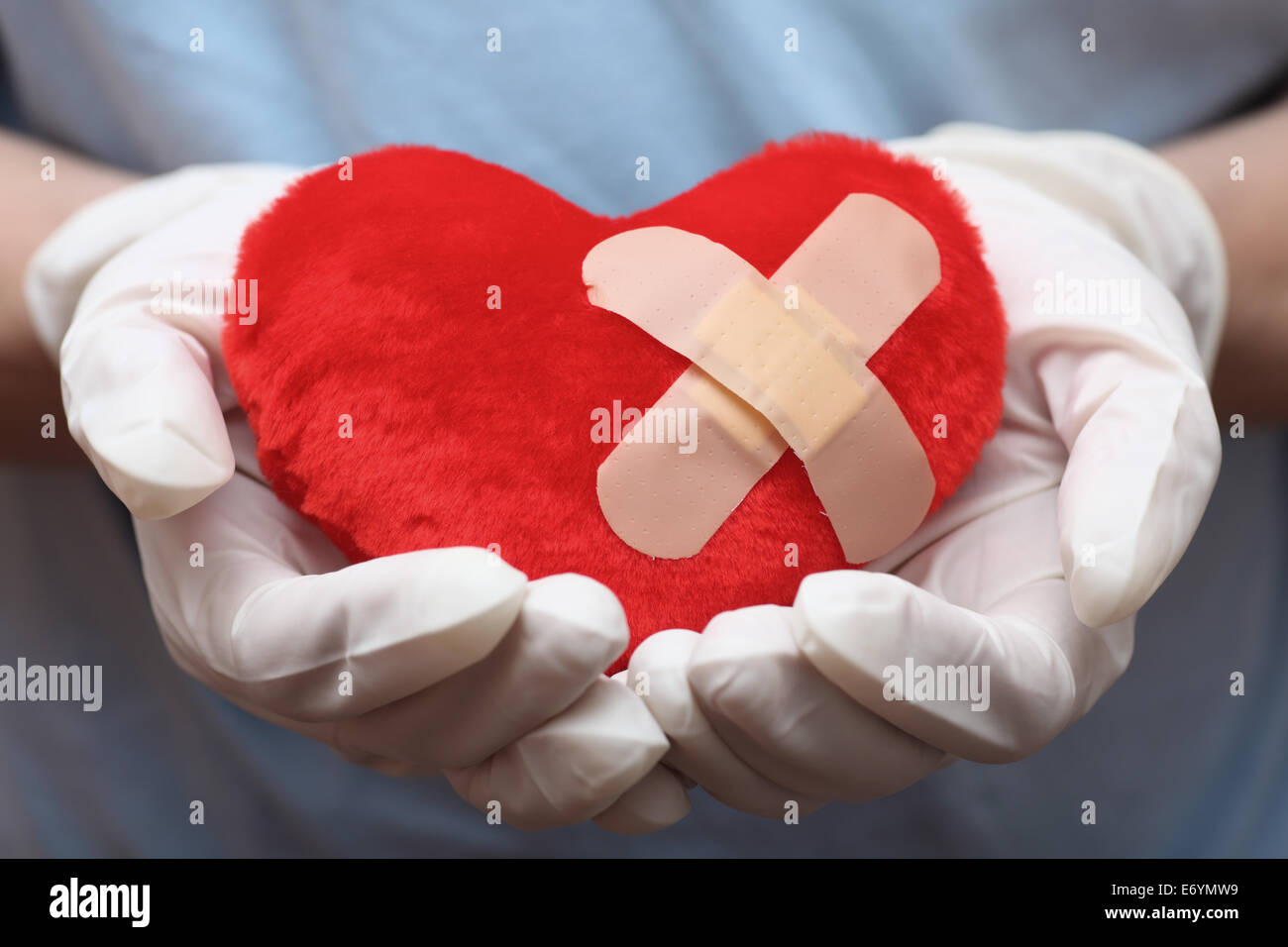 Rotes Herzform mit cross-Pflaster in die Hände des Arztes. Closeup. Stockfoto