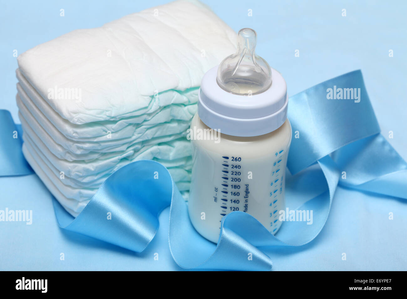 Baby-Flasche mit Milch, Windeln und blaues Band. Closeup. Stockfoto