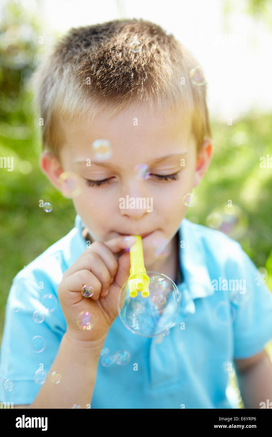 Kleiner Junge bläst Seifenblasen im freien Stockfoto