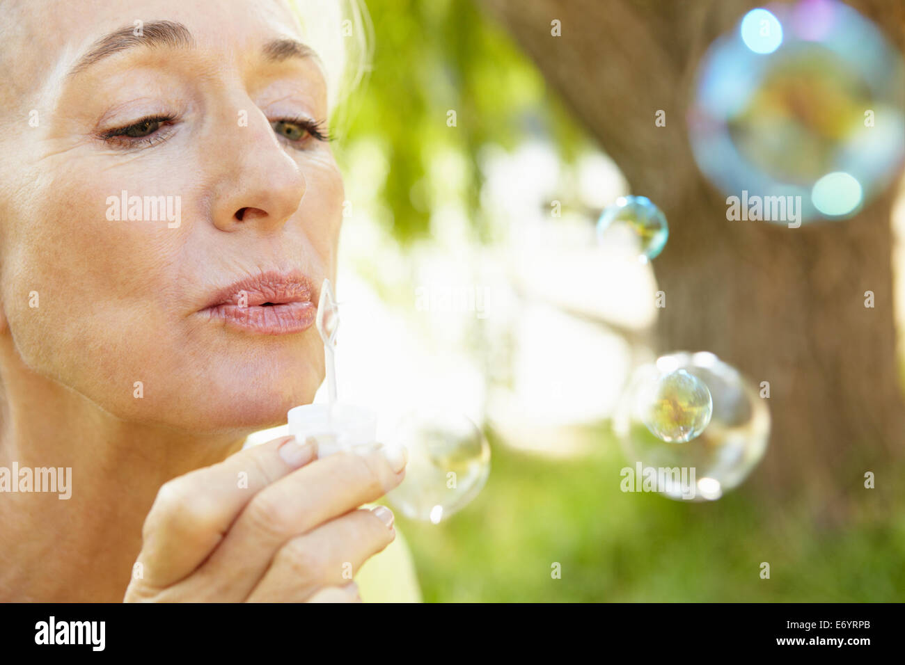 Ältere Frau bläst Seifenblasen im freien Stockfoto