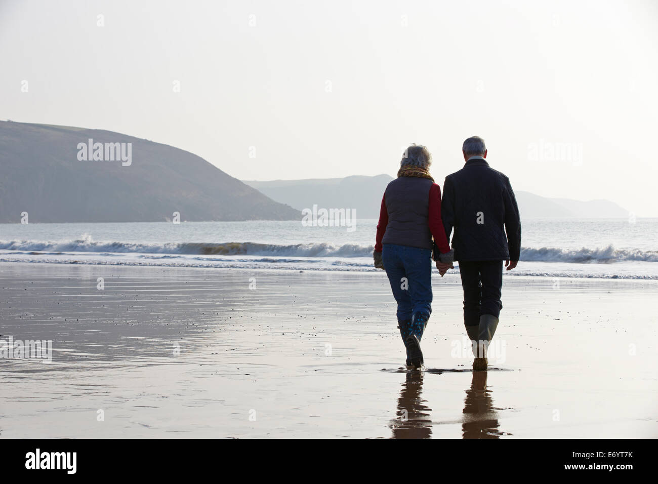 Älteres paar Winter Strand entlang spazieren Stockfoto