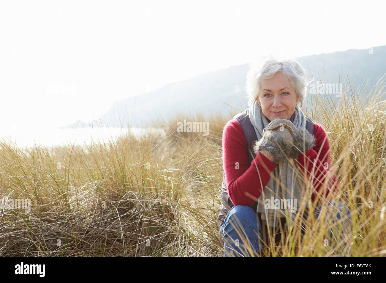 Ältere Frau Wandern durch die Sanddünen am Winter-Strand Stockfoto