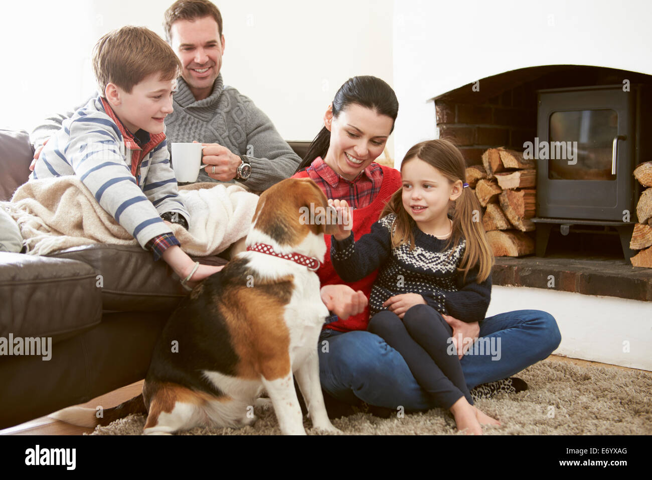 Familie drinnen entspannen und streichelte Haustier Hund Stockfoto