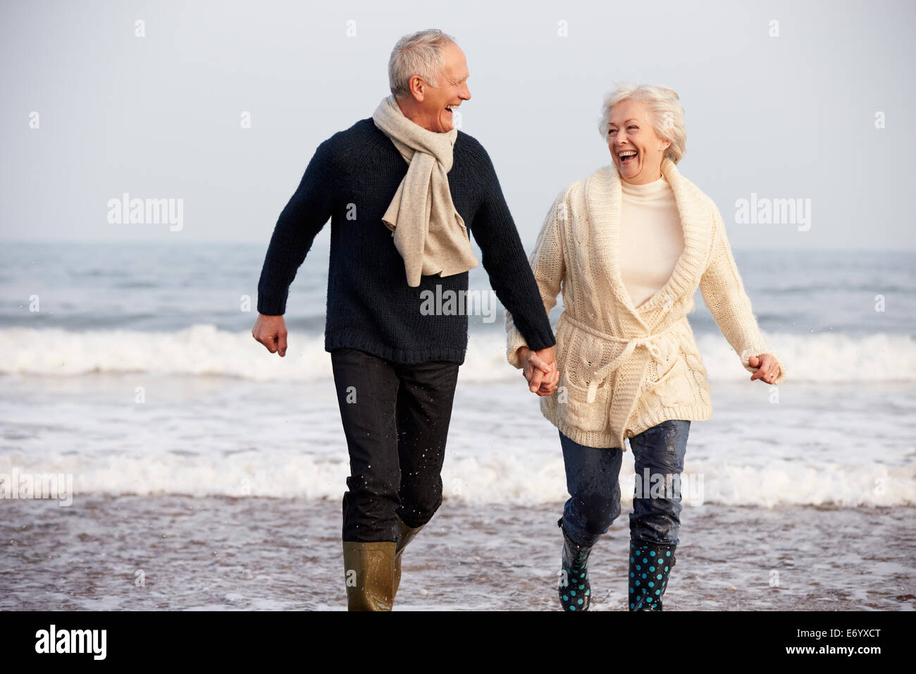 Älteres paar Winter Strand entlang laufen Stockfoto