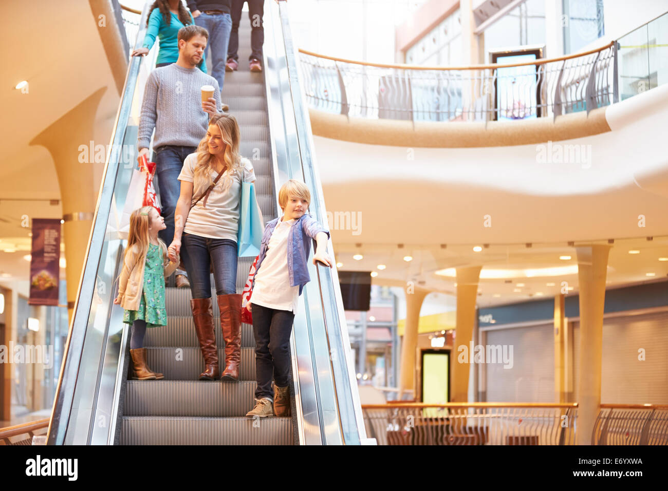 Mutter und Kinder auf Rolltreppe im Einkaufszentrum Stockfoto