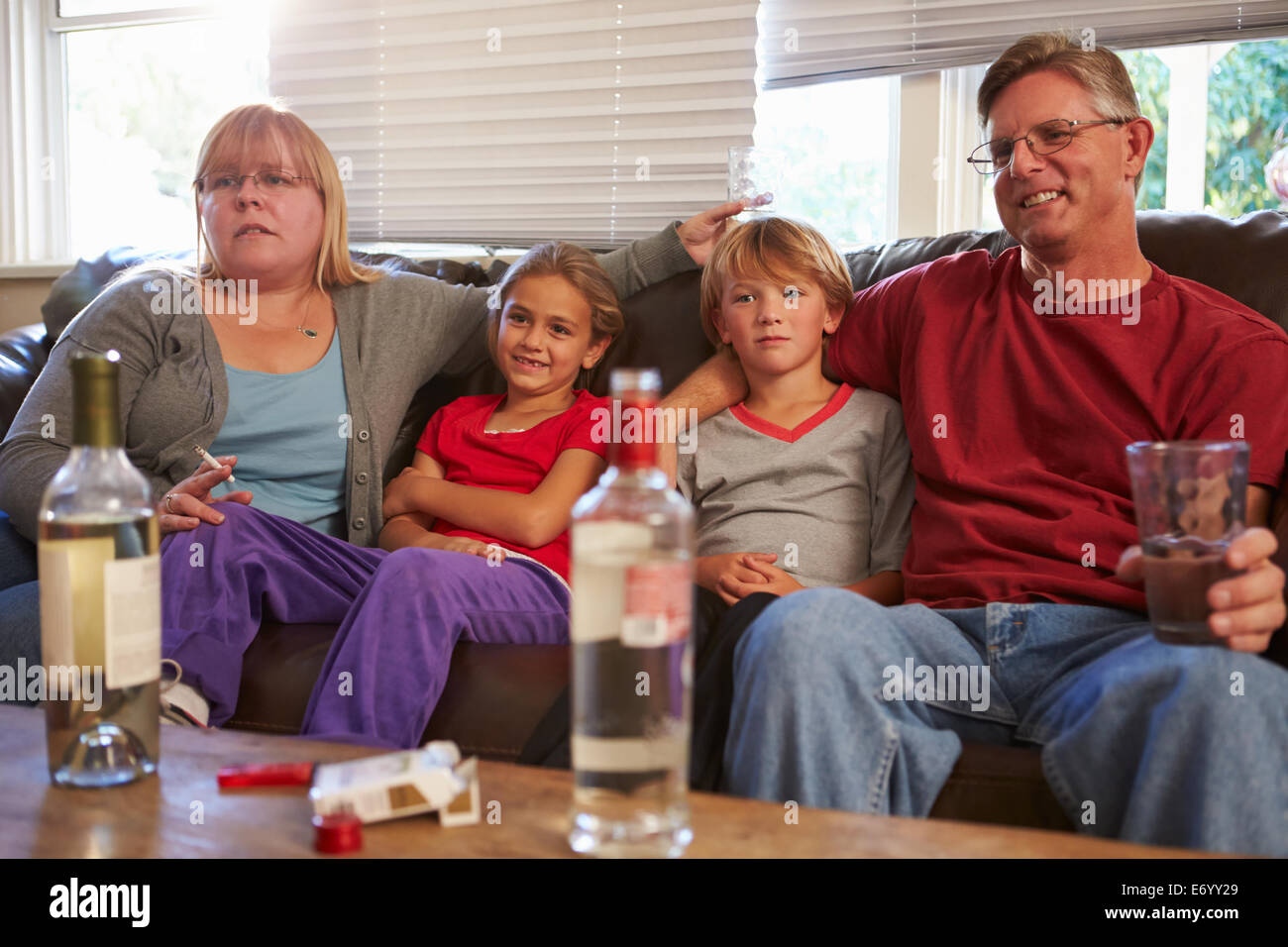 Eltern sitzen mit Kindern, Rauchen und trinken auf Sofa. Stockfoto