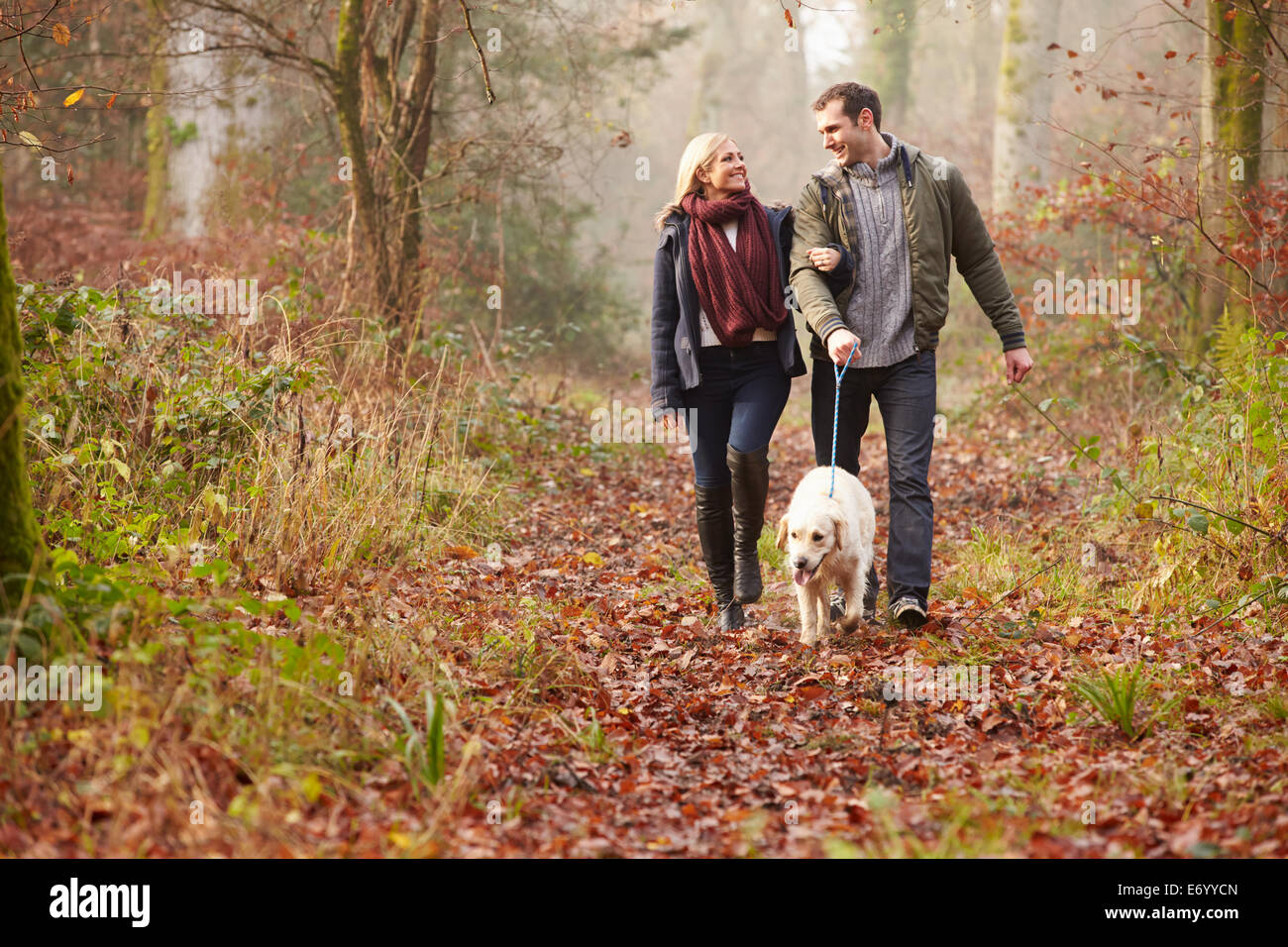 Paar Spaziergang mit Hund durch den Wald Winter Stockfoto