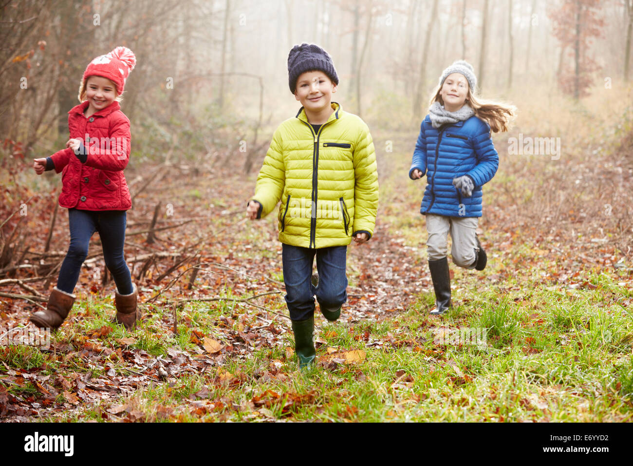 Drei Kinder laufen durch den Wald Winter Stockfoto