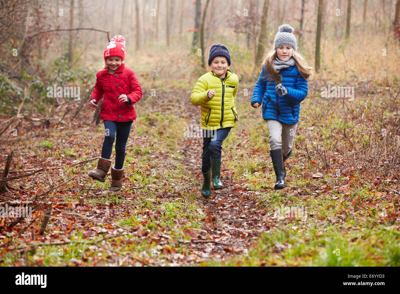 Drei Kinder laufen durch den Wald Winter Stockfoto
