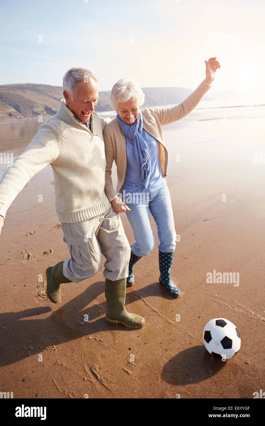 Älteres paar Fußballspielen am Winter-Strand Stockfoto
