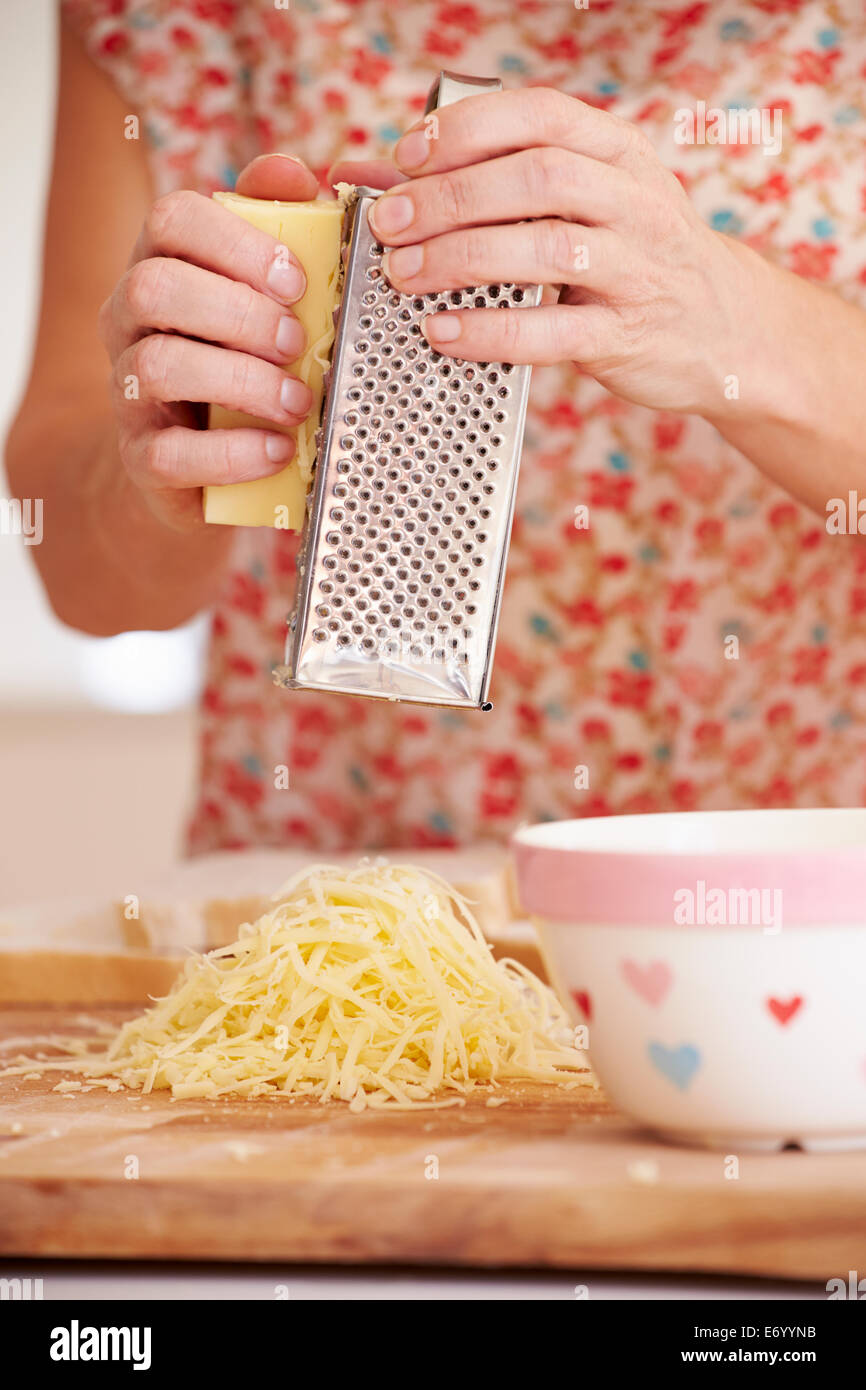 Nahaufnahme von Frau reiben von Käse In Küche Stockfoto