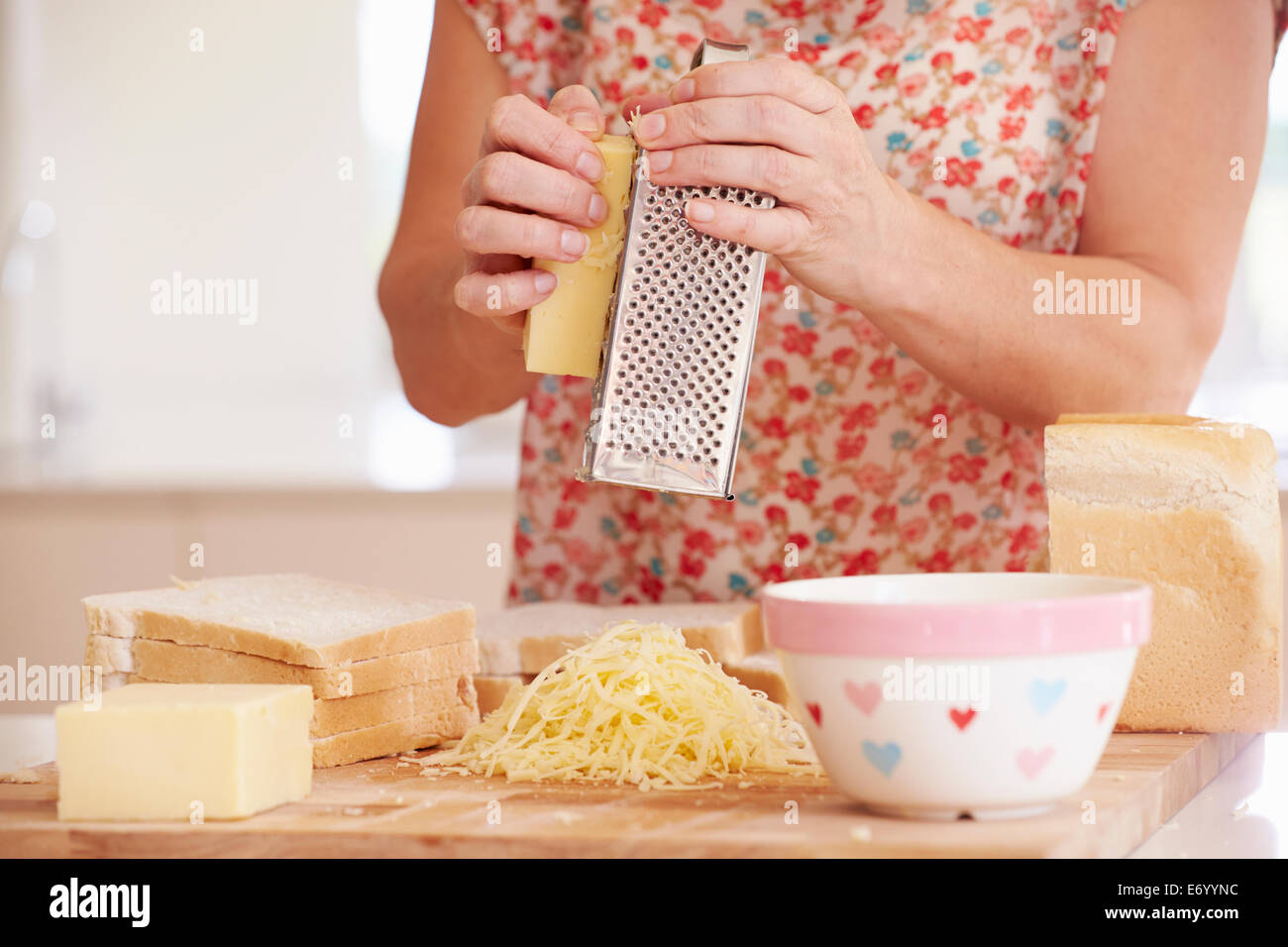 Nahaufnahme von Frau reiben von Käse In Küche Stockfoto