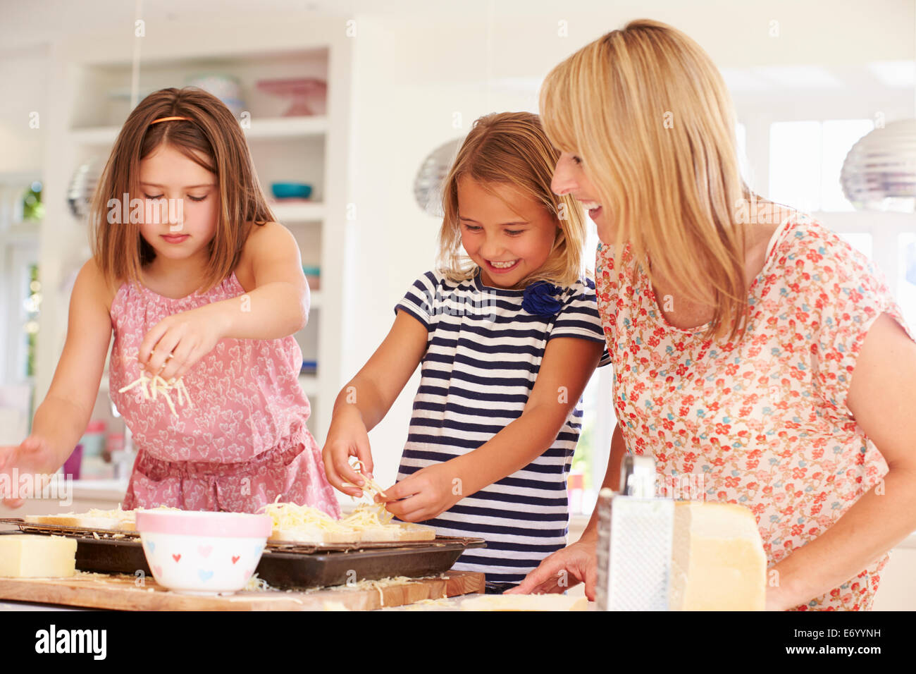Mädchen mit Mutter machen Käse auf Toast Stockfoto
