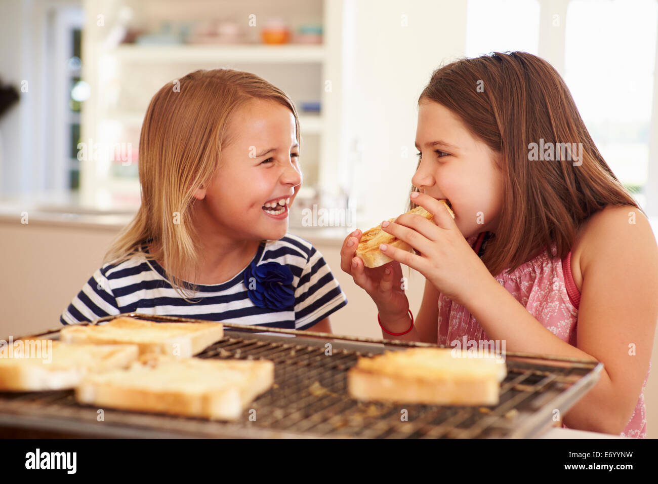 Zwei Mädchen essen Käse auf Toast In Küche Stockfoto