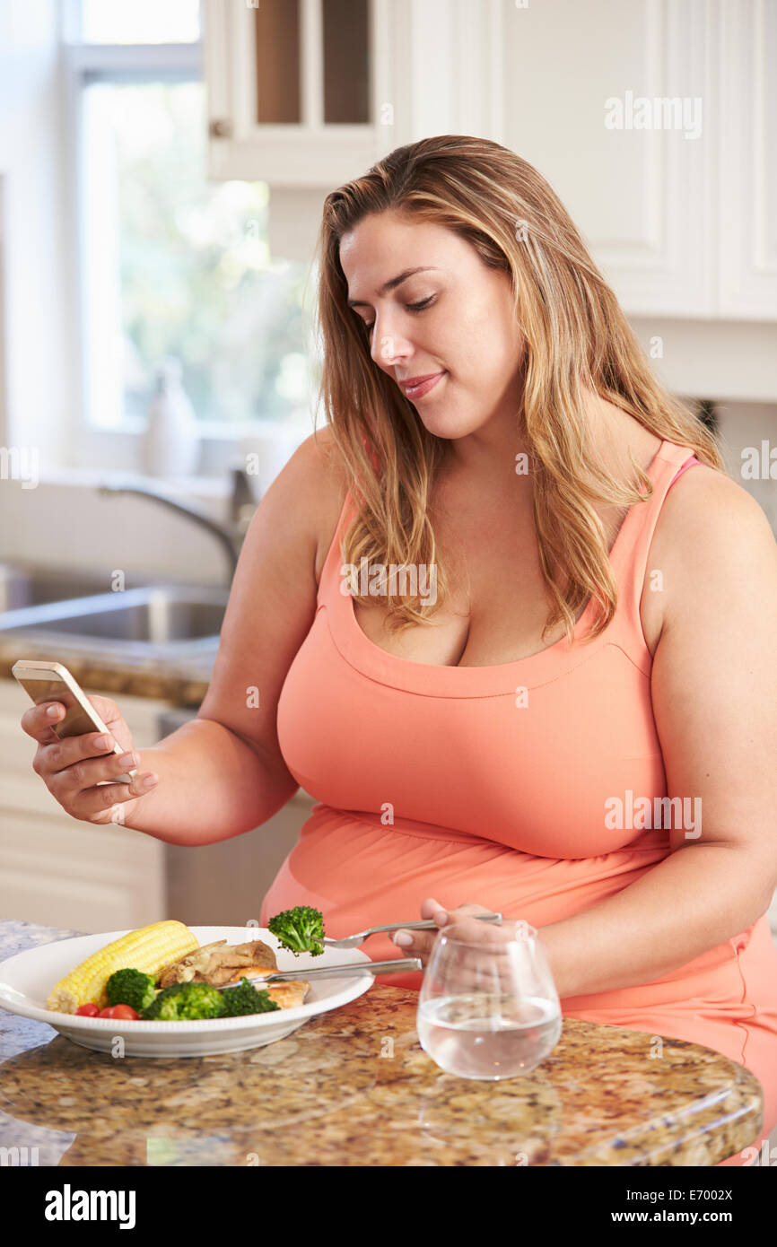 Übergewichtige Frau gesund essen und Handy Stockfoto