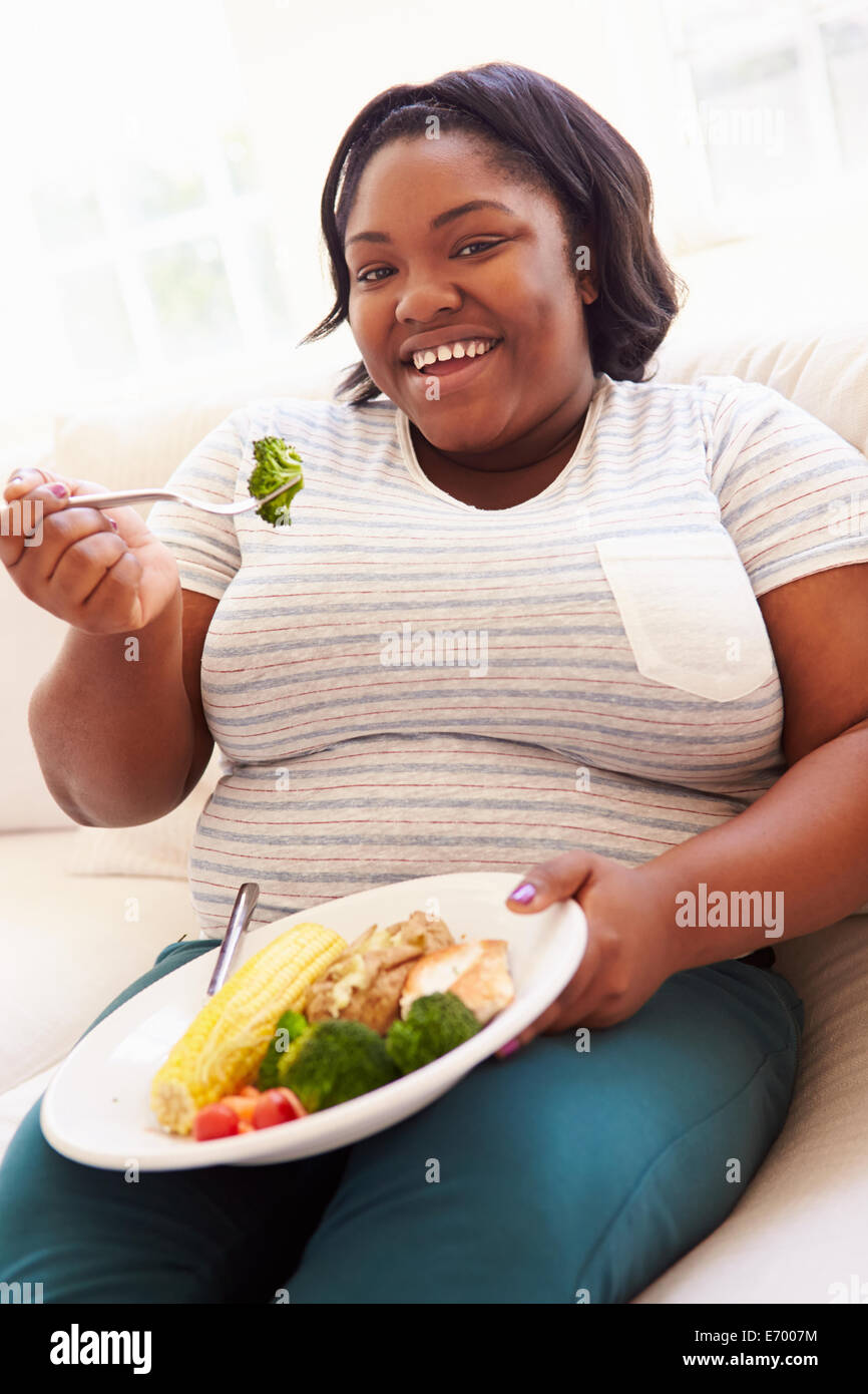 Übergewichtige Frau gesunde Mahlzeit auf Sofa Stockfoto