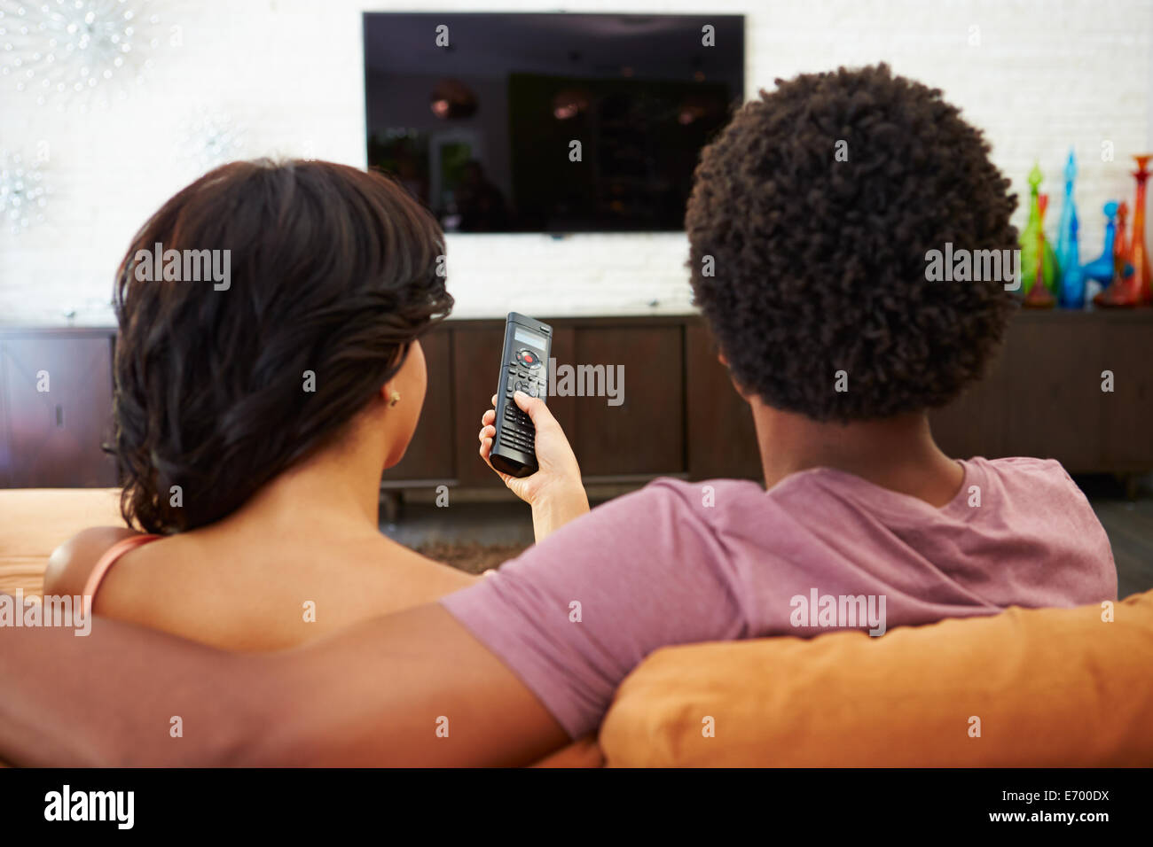 Rückansicht des Paares auf Sofa vor dem Fernseher zusammen sitzen Stockfoto