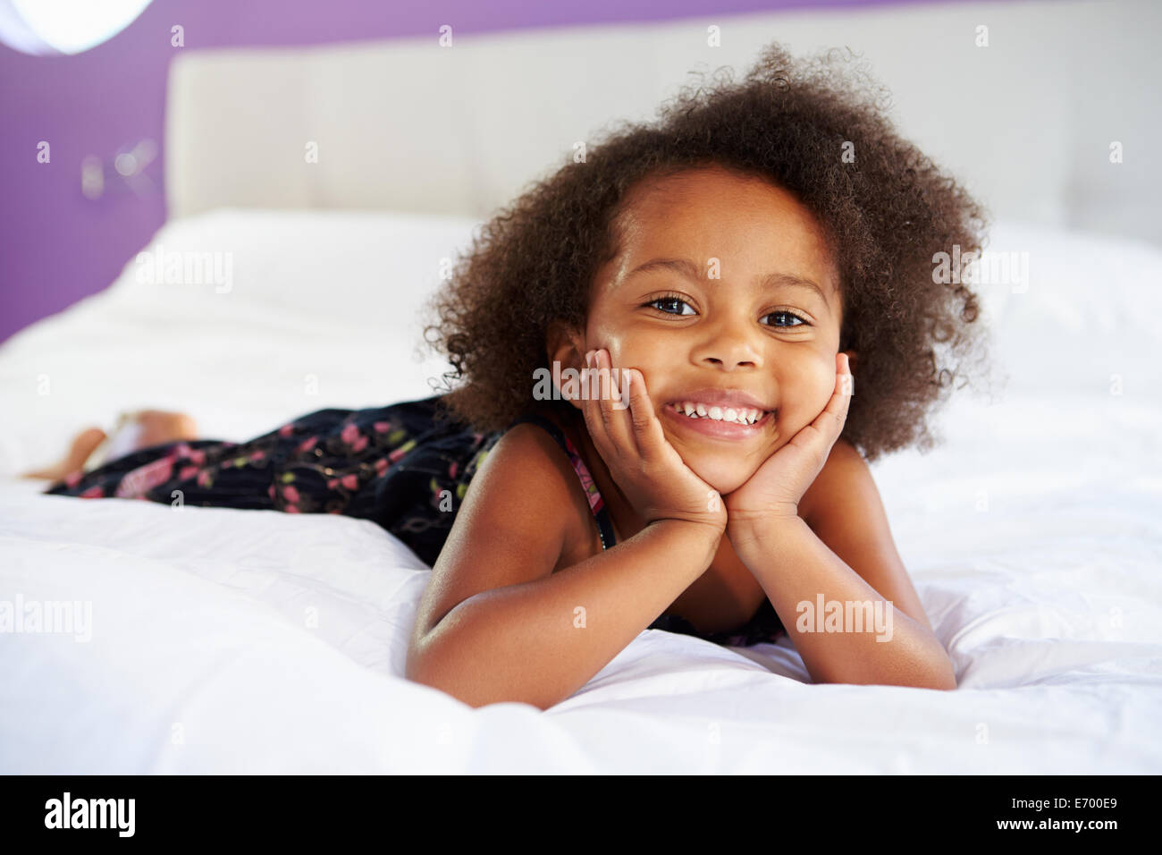 Niedliche kleine Mädchen liegend auf Bauch im Bett der Eltern Stockfoto