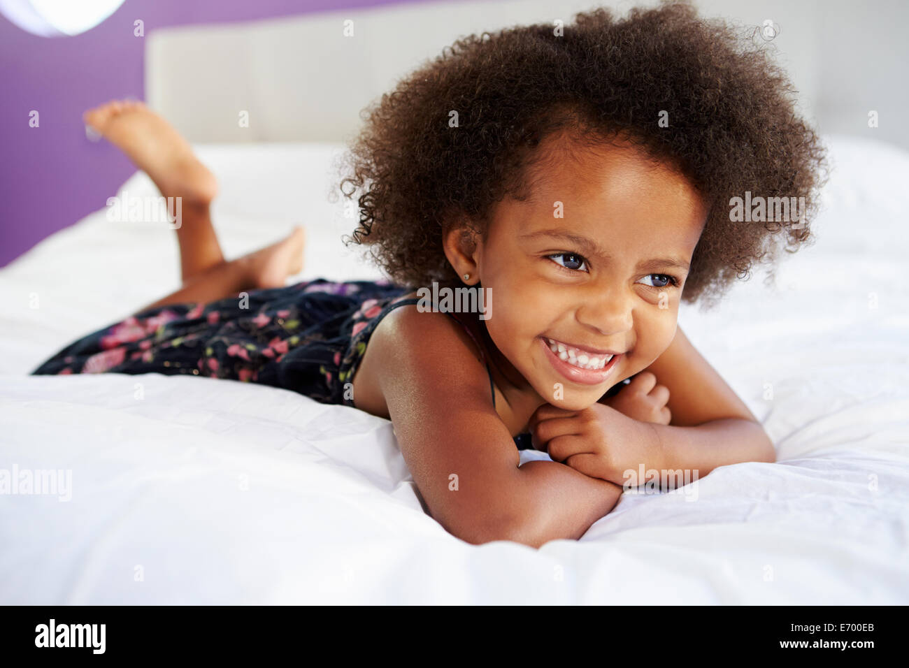 Niedliche kleine Mädchen liegend auf Bauch im Bett der Eltern Stockfoto