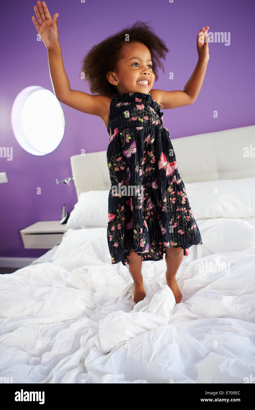 Niedliche kleine Mädchen springen auf Bett der Eltern Stockfoto