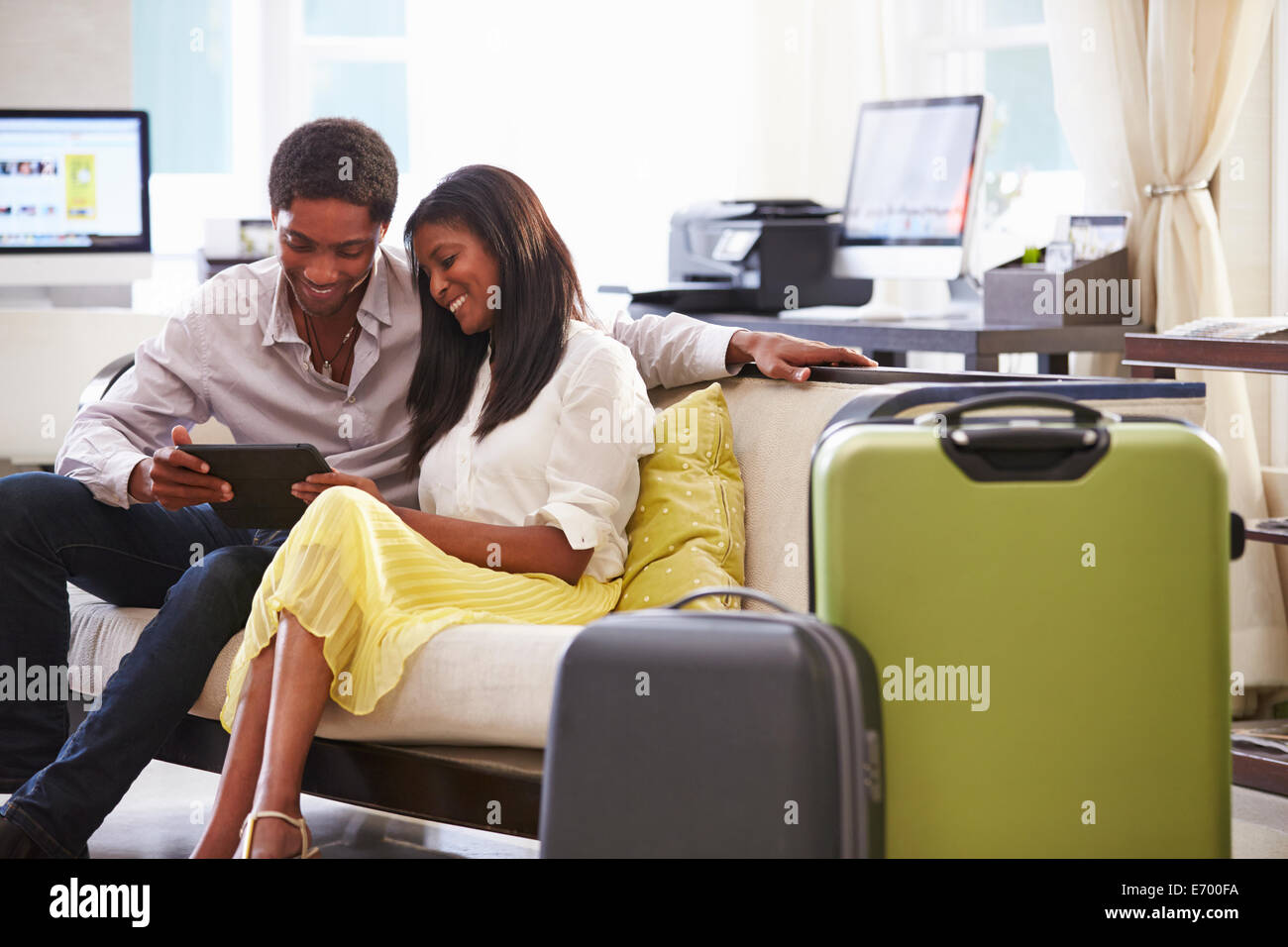 Paar sitzt In Hotellobby Blick auf Digital-Tablette Stockfoto