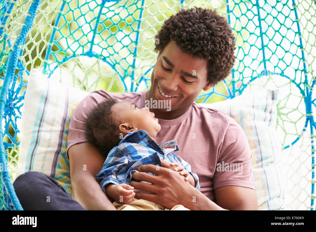 Vater mit Baby Sohn entspannend auf Garten-Schaukelsitz Stockfoto