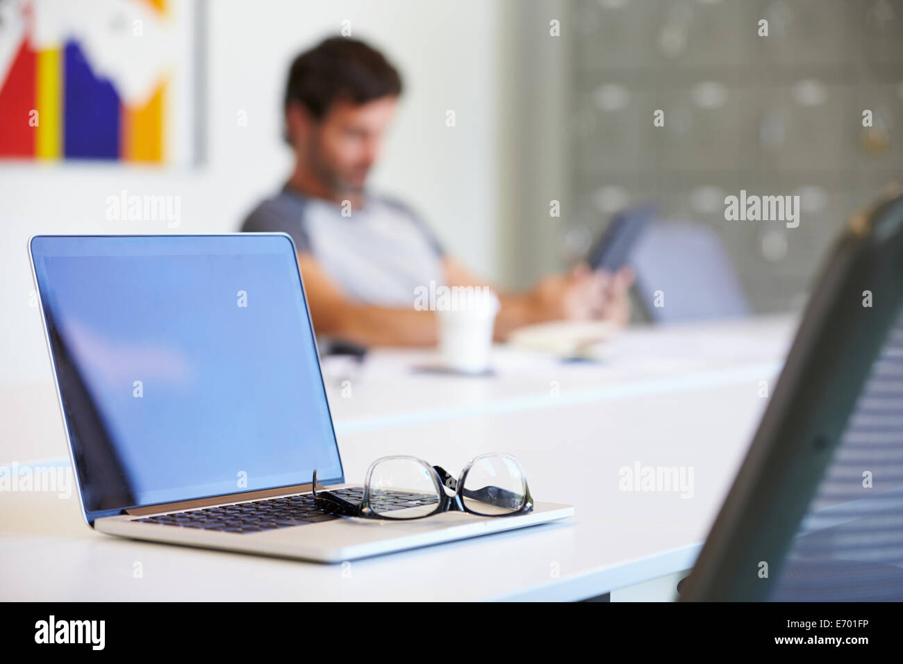 Laptop und Gläser auf Schreibtisch im Design-Studio Stockfoto