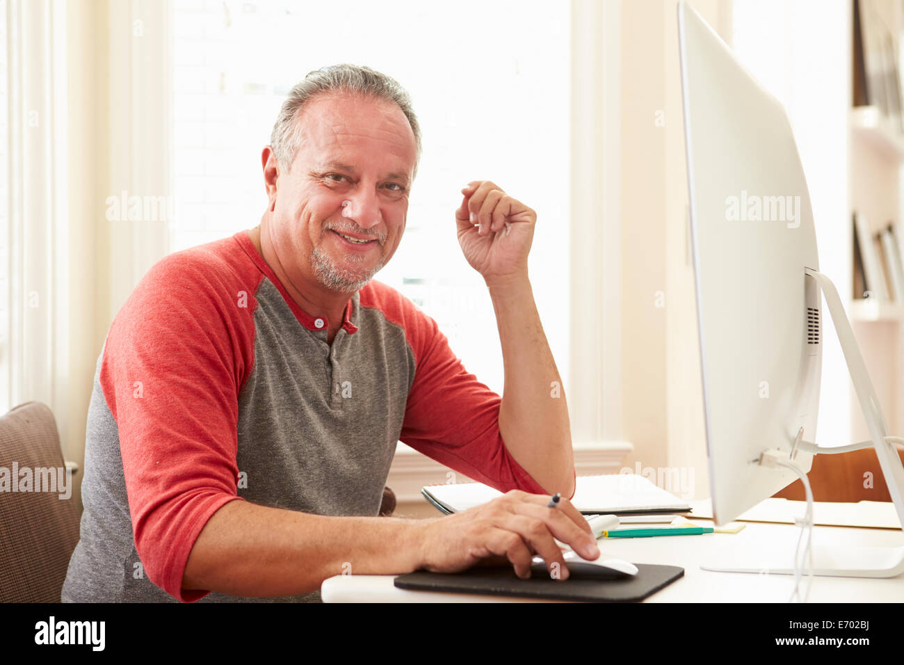 Portrait Of Senior Man mit Computer zu Hause Stockfoto